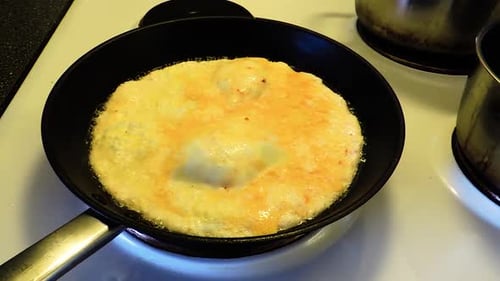 Egg Omelet Cooking in Frying Pan on Stove
