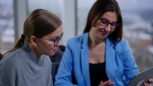 Female employees sitting in the modern office focused on the screen.