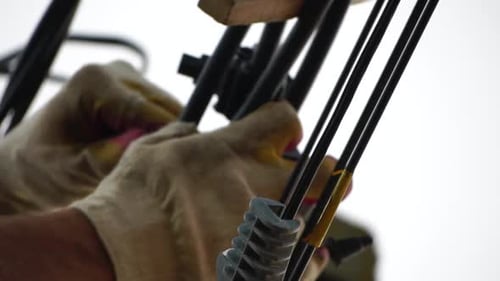 Worker Adjusting Wires with Gloves and Wrench