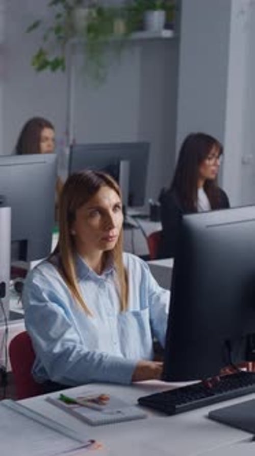 Focused Female Office Worker Typing at Desktop Computer in Modern Open Plan Workplace with