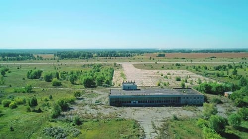 Aerial of a Small Abandoned Airport in a Valley with Green Trees and Fields on a Bright Sunny Day