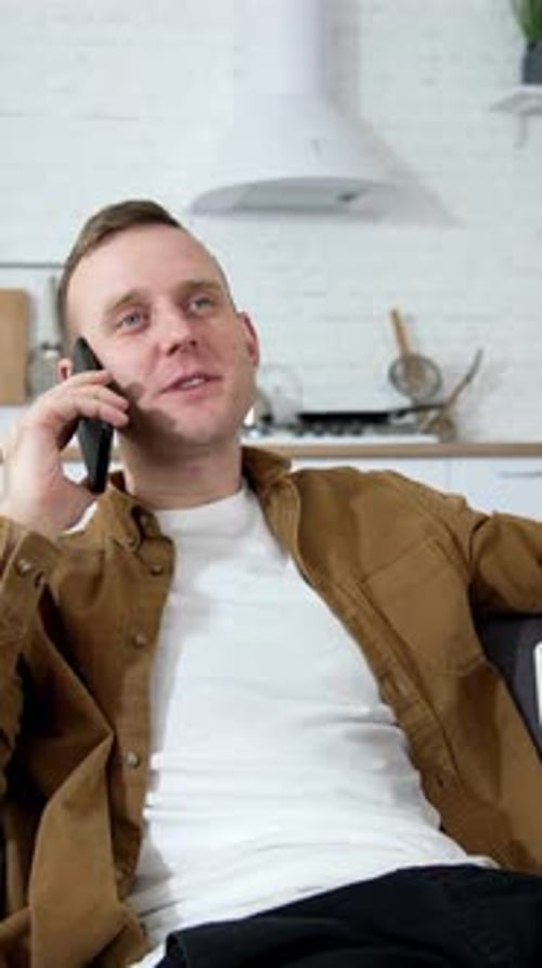 Happy Man Talking on Phone Sitting on Couch