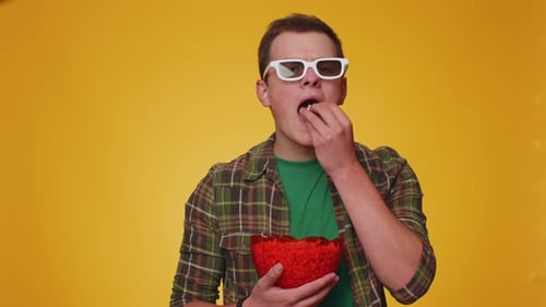 Young Man with 3D Glasses Eats Popcorn