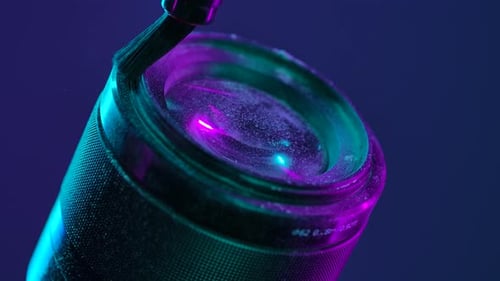 Cleaning Camera Lens with Brush Under Neon Light