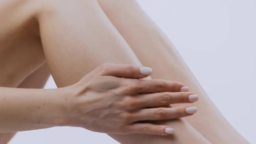 Woman Smoothing Lotion on Legs in Close Up