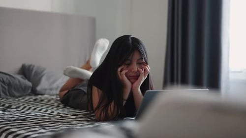 Woman Lies on Bed Using a Laptop