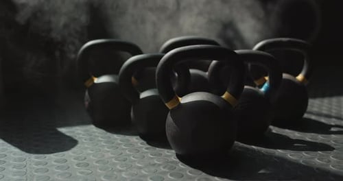 Black Kettlebells on Rubber Floor in Gym With Smoke