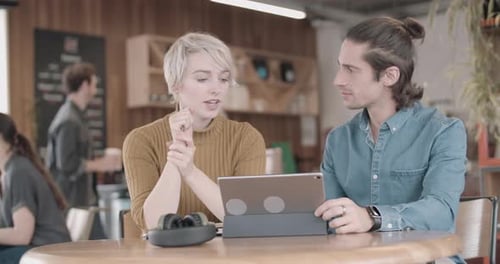 Freelancer in einer Besprechung in einem Café, die auf ein digitales Tablet schauen
