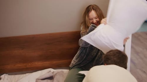 Feliz pareja joven teniendo una divertida pelea de almohadas
