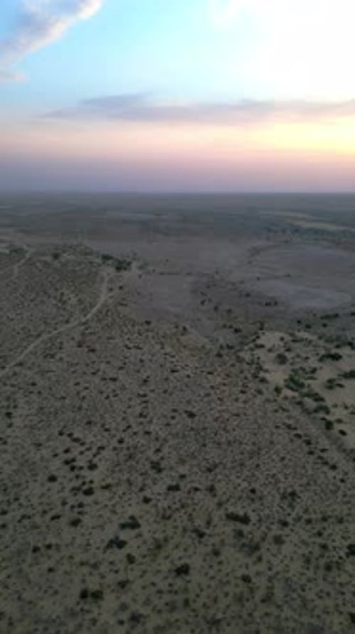 Aerial top view of golden sand dunes with greenery and dramatic sky in Jaisalmer, Rajasthan