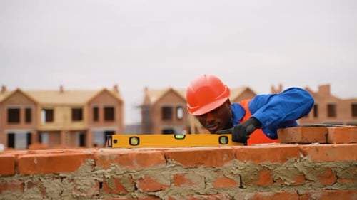 Un maçon vérifie le niveau du mur sur le chantier de construction d'une maison de ville