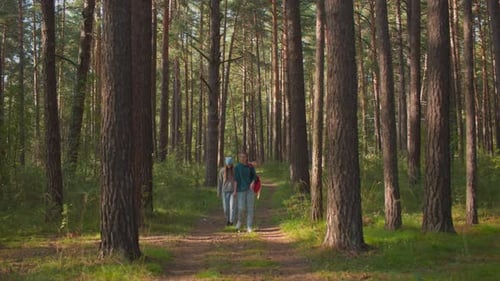 Friends Walking Through Serene Forest Path with Red Backpack and Draped Handkerchief