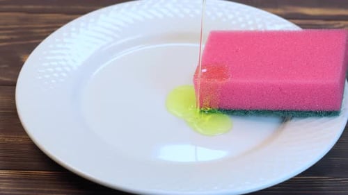 Soap Being Poured Onto Sponge on White Plate