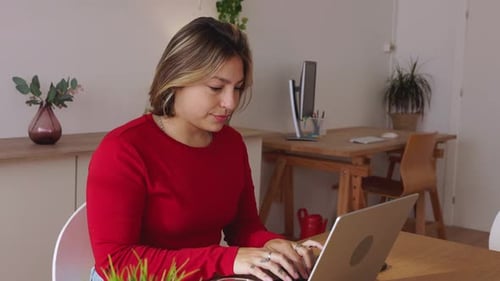 Woman Works on Laptop at Desk in Apartment