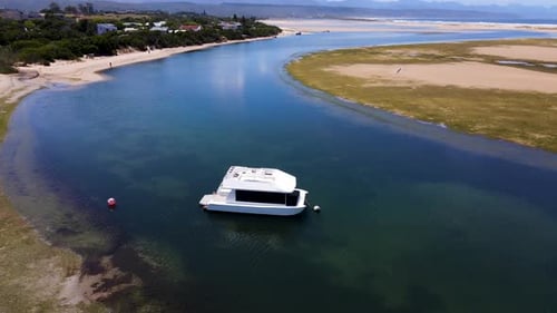 Revelación aérea de una casa flotante blanca anclada en la laguna de Plettenberg Bay