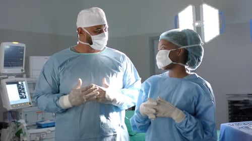 Portrait of diverse surgeons wearing surgical gowns in operating theatre, slow motion