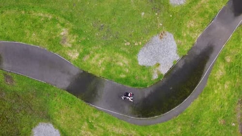 Eine Drohnenaufnahme eines jungen Radfahrers von oben nach unten auf einem Pumptrack.