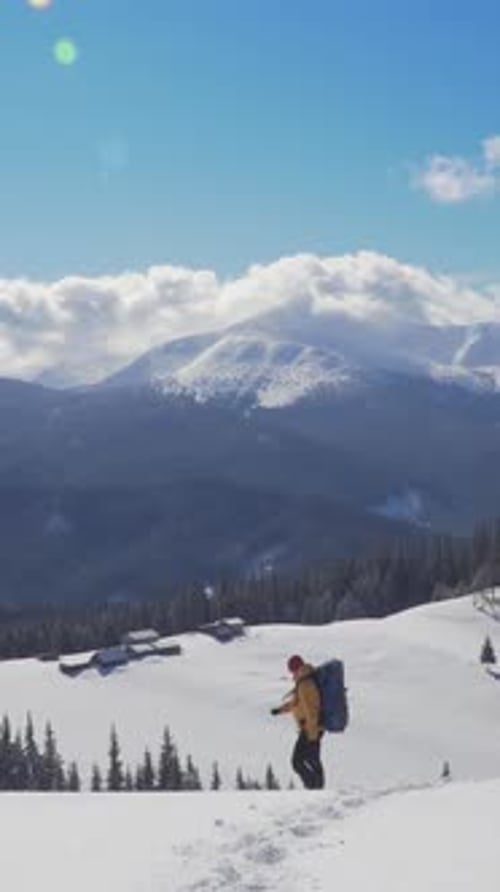 Hiker Ascending Snowy Mountain Trail with Breathtaking Views of Peaks on Sunny Winter Day