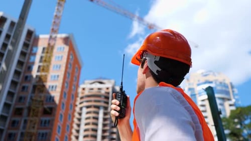 Male Construction Worker with Walkietalkie at Construction Site Standing Outdoors Business Building