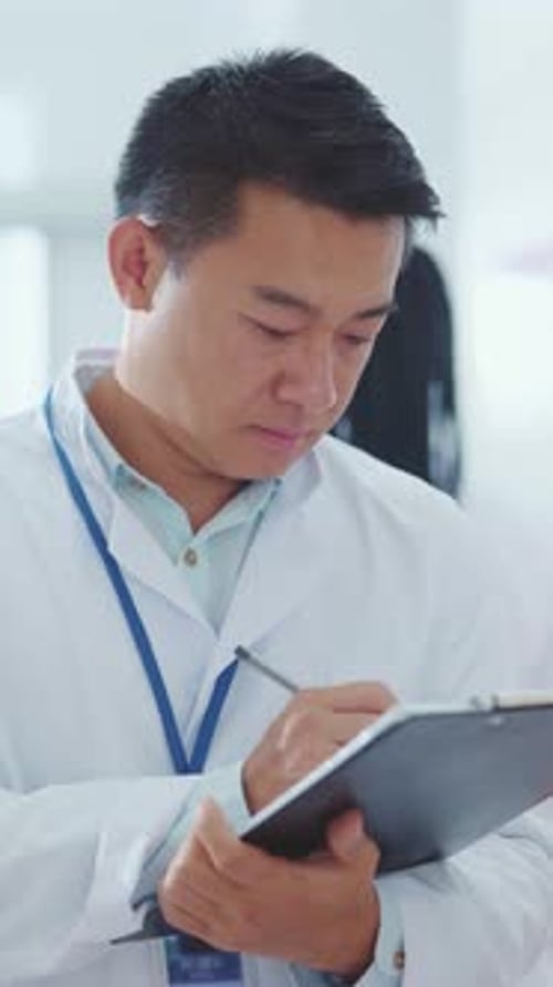 Focused Doctor Writes on Clipboard in Hospital Setting