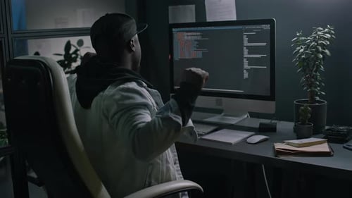 Tired Black Male Programmer Writing Code at Night and Stretching