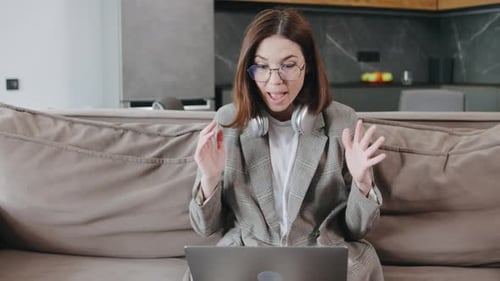 A Young Businesswoman Works From Home on Their Laptop Comfortably on the Couch Embodying