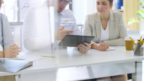 Happy business team discussing technology behind glass in modern office