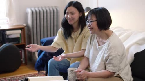 Woman and senior woman chat on couch indoors