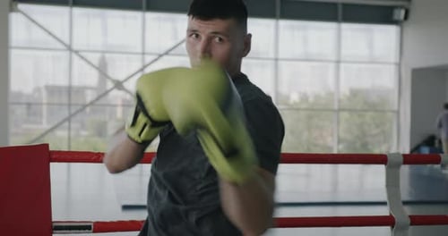 Slow Motion Portrait of Muscular Sportsman Boxer Training in Gym Punching Air with Gloves and