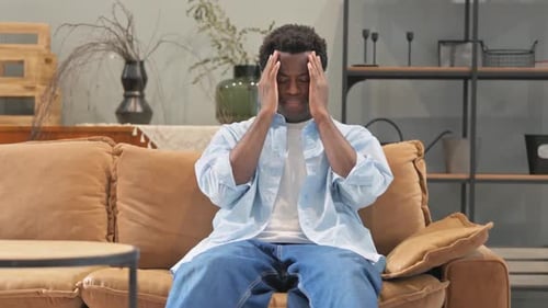 Adult rubbing Temples on Brown Couch Indoors