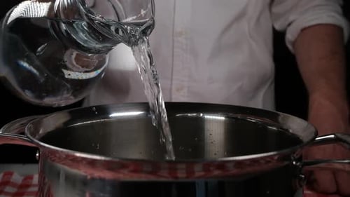 Water Pouring into Stainless Steel Pot in Kitchen
