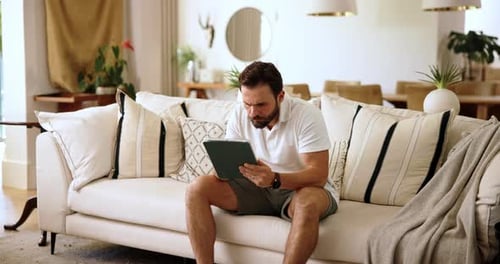 Man on Couch Using Tablet in Bright Home