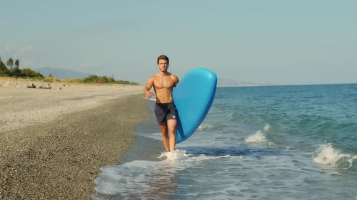 Man with Paddle Sup Board on the Beach