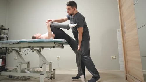 Professional Male Chiropractor Physiotherapist Treating Female Patient in Rehabilitation Center