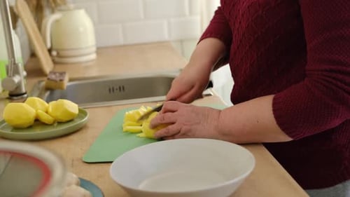 Woman cutting potatoes on a cutting board