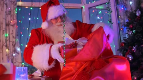 Santa Claus Placing Gift in Bag Indoors
