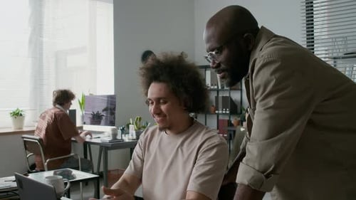 Programmer Showing New Software to Coworker, Both Looking at Laptop Screen