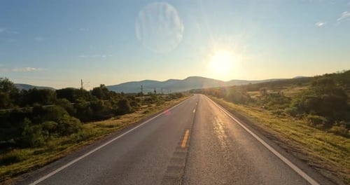 Driving a Car on a Road in Norway at dawn.