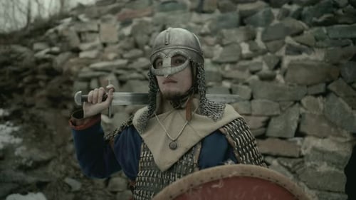 Portrait of Medieval Warrior Holding Sword and Shield near Fortress Wall