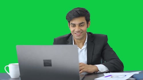 Happy Indian manager talking to employees through video call Green screen