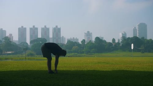 Stretching training young man exercising on grass at park outdoors