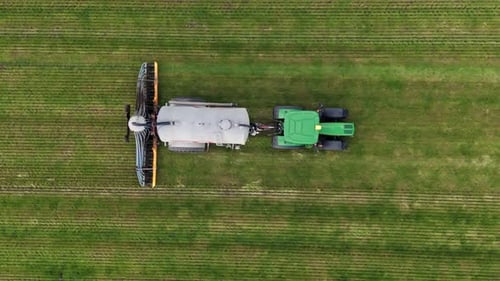 Agricultura aérea: tractor esparciendo estiércol en exuberantes campos verdes, de arriba hacia abajo
