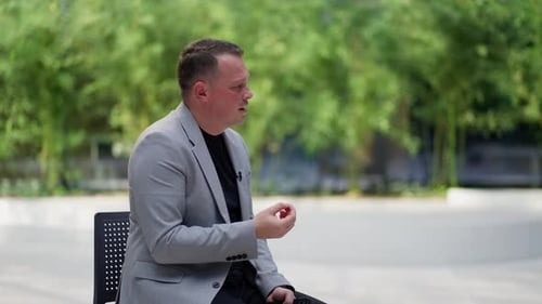 Man in Gray Jacket Talking in Outdoor Interview