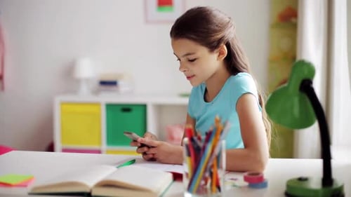 Child Using Phone at Desk with Open Book