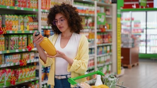 Woman Choosing Orange Juice Bottle in Supermarket