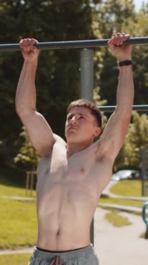 Athletic Caucasian Topless Muscular Man Doing Pull Ups Exercises on Horizontal Bar Pumping Up Back