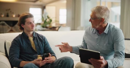 Senior Man and Young Adult Conversing with Tablet