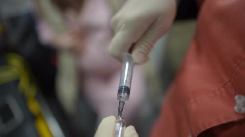 Nahaufnahme einer Krankenschwester, die eine Spritze mit Medikamenten aus einer Glasampulle füllt, um sie einem Patienten zu injizieren
