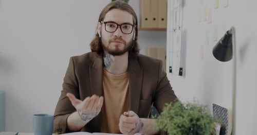 Portrait of Confident Young Man Speaking and Gesturing Making Online Video Call From Office