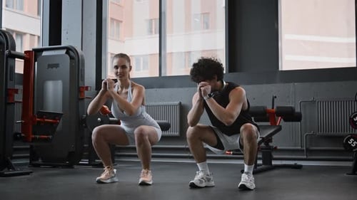 Personal Coach Helping Woman with Exercise during Workout in Gym